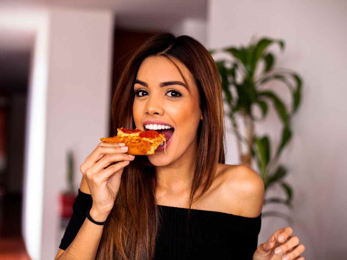 ragazza mangia fetta di pizza