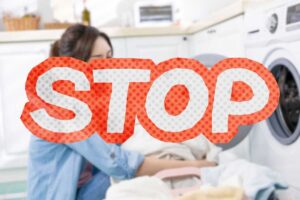 donna mette indumenti in lavatrice e scritta stop