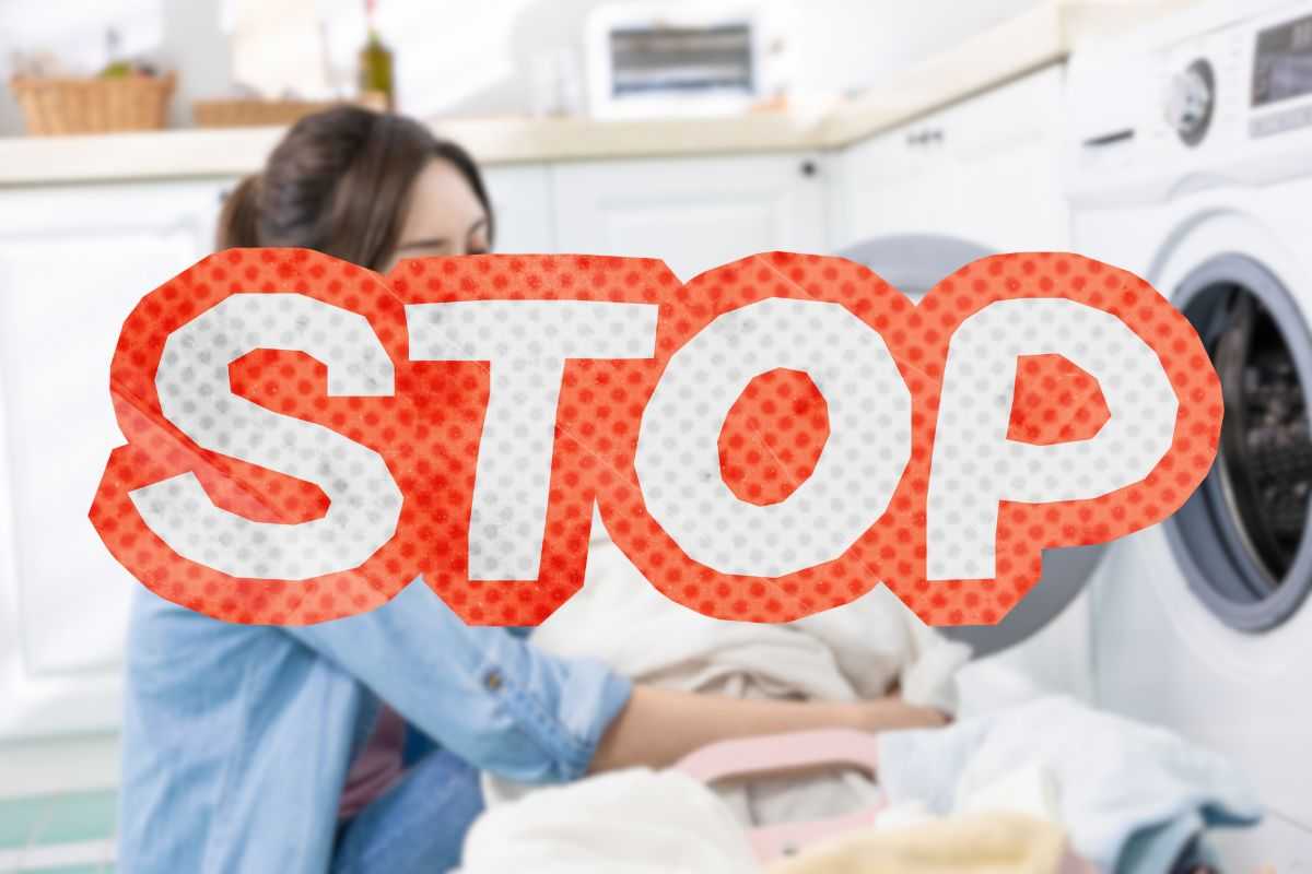 donna mette indumenti in lavatrice e scritta stop