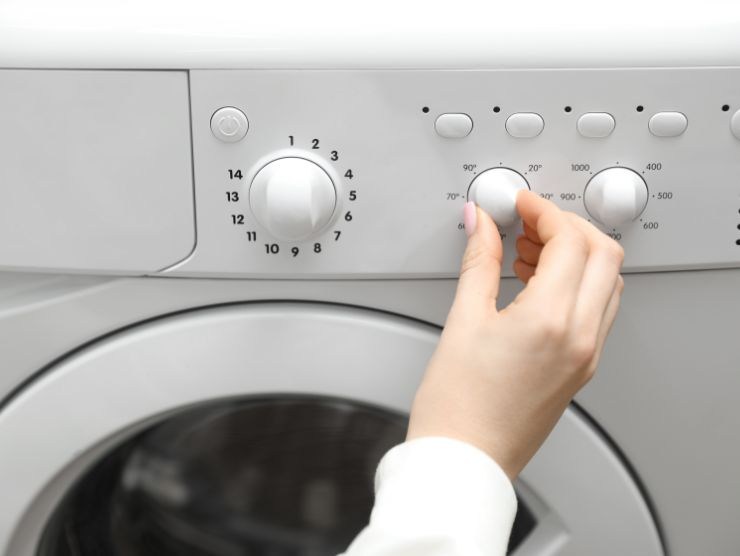 mano che gira manopola sulla lavatrice