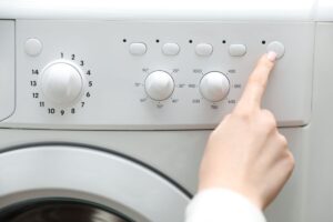mano che preme tasto sulla lavatrice
