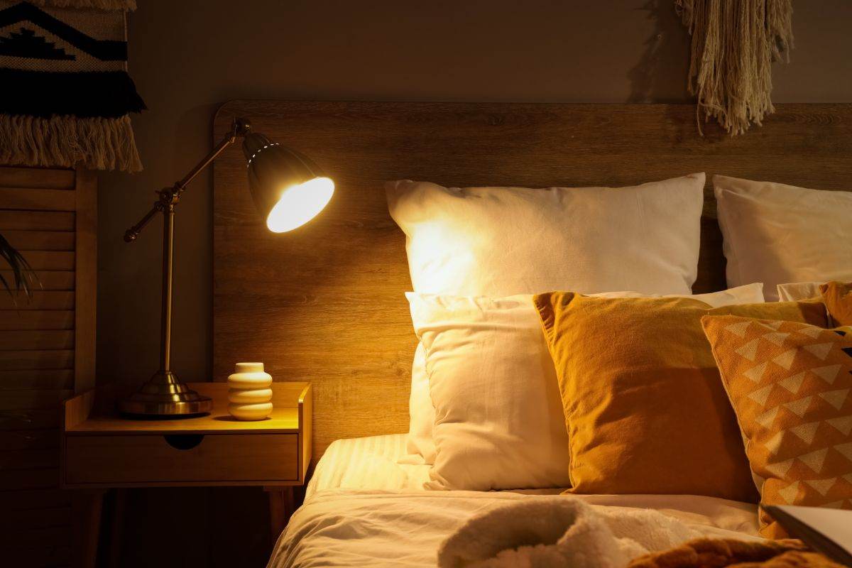 letto accanto ad un comodino con la lampada