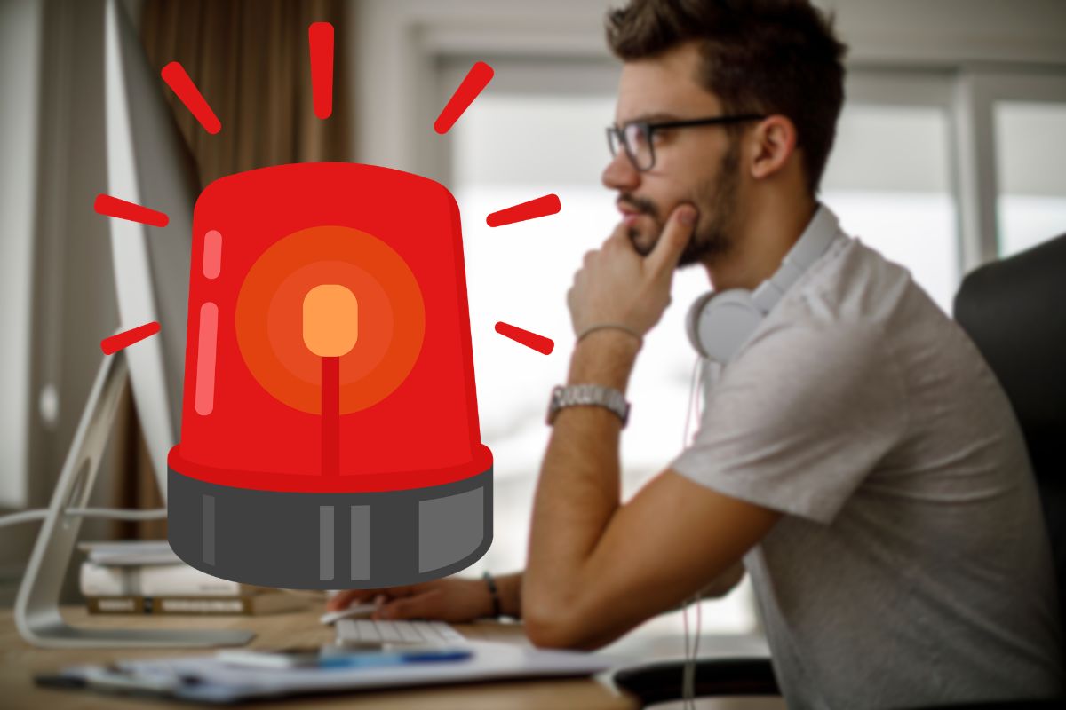 uomo al pc e segnale di pericolo