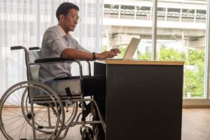 uomo seduto sulla sedia a rotelle davanti al pc