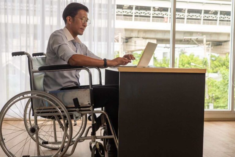 uomo seduto sulla sedia a rotelle davanti al pc