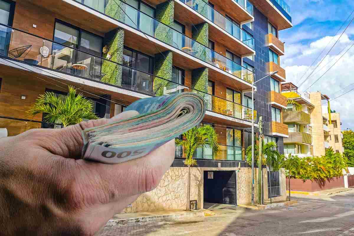 condominio e mano che mantiene una mazzetta di soldi